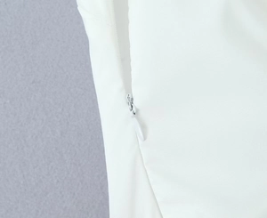 Detail of high-quality invisible zipper on a white halter-neck backless mini dress