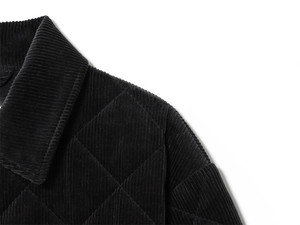 Detail of black corduroy jacket showing diamond quilting and collar texture