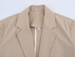 Close-up of khaki blazer lapel with textured fabric and white size S inner label