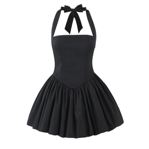 Detail of a black halter mini dress with a large bow tie neck and pleated flare skirt