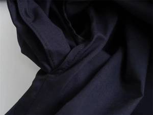 Macro shot of side seam pocket detailing on dark poplin long sleeve shirt