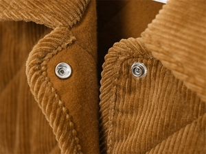 Macro detail of brown corduroy fabric with silver metal snap buttons and inner lining