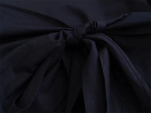 Detailed close-up of the elegant knot design on a black poplin long sleeve shirt for women