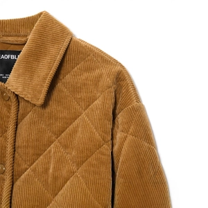 Detailed view of brown corduroy quilted jacket with brand label and diamond stitching
