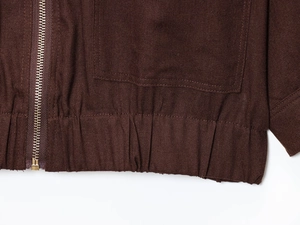 Detailansicht einer schokobraunen Jacke mit Metallreißverschluss und großer aufgesetzter Tasche