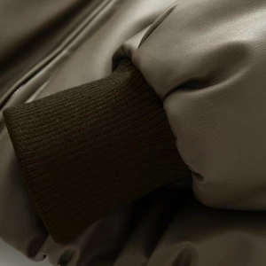 Detail of faux leather sleeve with brown ribbed knit cuffs on chic autumn jacket