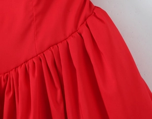 Detail of red halter dress featuring dense ruched texture and high-quality stitching