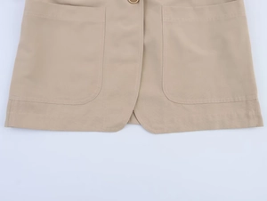 Detail of khaki blazer hem featuring large symmetrical patch pockets and woven texture