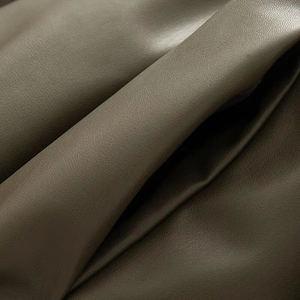 Detailed macro shot of deep olive green PU leather fabric showing fine litchi texture