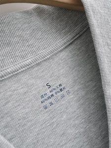 Detail of gray ribbed knit T-shirt tag showing S size and cotton rayon fabric blend