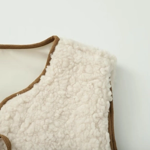 Close-up of cream fleece vest with brown suede binding and high-quality stitching details