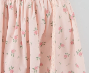 Detail of pink floral dress featuring rose print and delicate lace trim on soft fabric