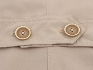 Close-up of beige twill fabric details with dual resin buttons and neat stitching