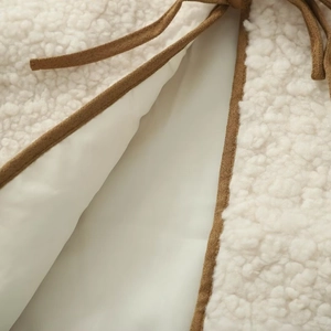 Detail of plush cream fleece fabric with brown piping and delicate bow-tie closure