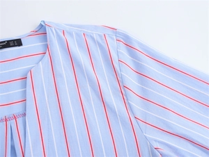 Detail of blue striped cotton shirt featuring a chic bow and soft V-neckline texture