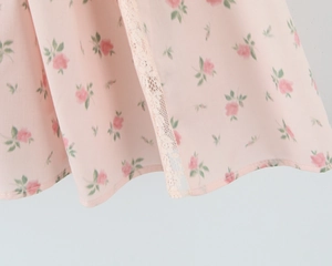 Detail of pink floral fabric with delicate lace trim and rose pattern stitching