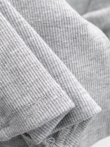 Macro shot of grey ribbed knit fabric showing neat double-needle stitching and texture