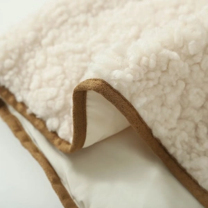 Close-up of soft sherpa fleece fabric texture with brown trim and dense stitching detail