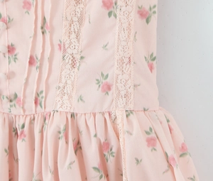 Detail of pink floral dress featuring white lace trim and delicate fabric buttons