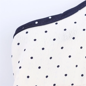 Close-up of white fabric with navy blue polka dots and high-quality edge stitching detail