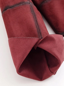 Detailed view of dark burgundy suede fabric with precise stitching and matte texture