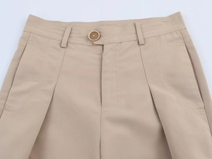 Detail of beige pleated trousers with button closure and slanted pockets texture