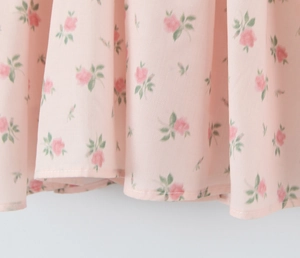 Detail shot of light pink floral fabric with fine rose patterns and neat stitching