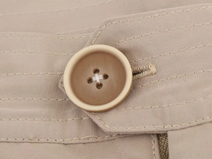 Detailed macro view of four-hole gradient brown buttons on khaki twill fabric blazer