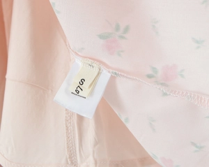 Close-up of fabric label showing size S and made in china on pink floral summer dress