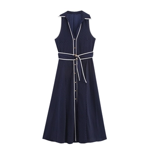 Detail of navy sleeveless polka dot dress featuring V-neckline with white contrast piping
