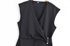 Détail de la robe noire sans manches à col en V avec épingle dorée et texture du tissu