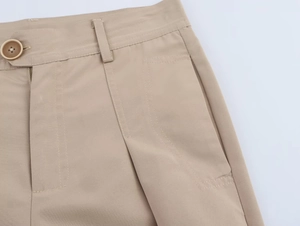 Detail of khaki trousers featuring resin button closure and durable belt loops