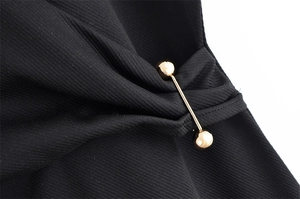 Détail du tissu en sergé noir avec épingle décorative en métal doré de style haltère