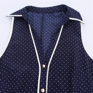 Detail of navy blue polka dot dress with V-neck collar and gold metal buttons