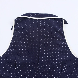 Detail of navy blue polka dot dress featuring a white contrast lapel collar and sleeveless cut