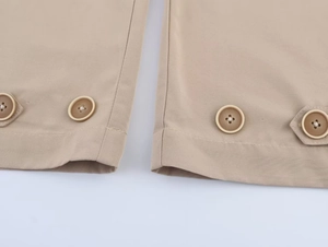 Close-up of khaki trousers cuffs with decorative buttons and adjustable tabs details