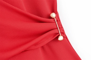 Détail d'une robe en sergé rouge avec barre dorée créant un effet de plissé élégant et chic