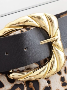 Gros plan d'une ceinture en cuir noir avec une grande boucle en métal doré torsadé
