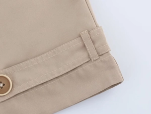 Detail of khaki twill fabric with classic brown button and double stitching craftsmanship