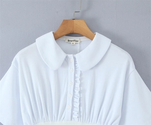 Close-up of white Peter Pan collar dress with ruffle details and brand woven label