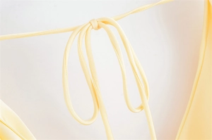 Dettaglio dell'abito in raso giallo chiaro con delicato nodo a coulisse e trama setosa