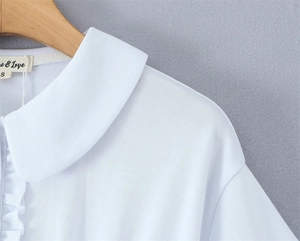 Detail of white cotton shirt with ruffled Peter Pan collar and pleated lace texture