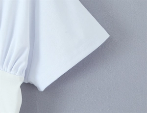 Detailed macro view of white short sleeve knit top showing pleated cuffs and double stitching
