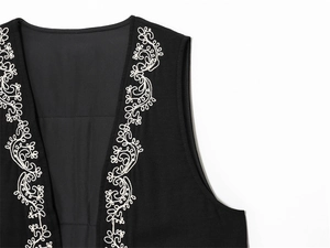 Detail shot of white vine floral embroidery on the black sleeveless fashion waistcoat