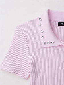Close-up of pink ribbed knit polo shirt with crystal embellishments on the collar