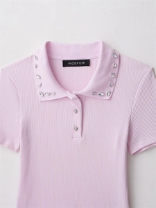 Detail of pink knit polo shirt featuring rhinestone collar accents and ribbed texture