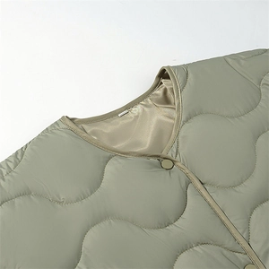 Detail of sage green quilted jacket showing round neckline and premium piping finish