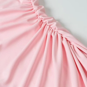 Detail view of the elegant ruching and gathered soft pink fabric on the summer dress