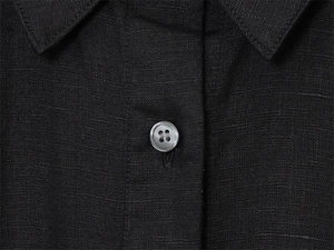 Detailed close-up of a black linen shirt collar featuring a classic button and fabric texture