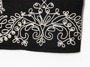 Detail of white wave embroidery on black fabric showing premium stitching and texture